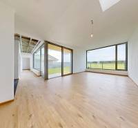 A spacious room in a family house with wooden flooring and large windows.
