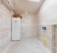 A bathroom in a family house with tiles and a boiler on the right side.