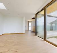 A spacious room with large windows in a family house, bright walls, wooden floor.