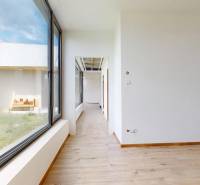 A hallway in a family house with a large window and a view of the grassy exterior.