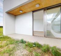 A terrace with tiles and glass doors of a family house overlooking the garden.