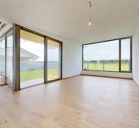 A spacious living room with wooden flooring and large windows in a family house.