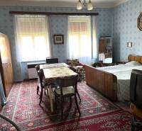 A bedroom in a family house with wooden furniture, a carpet, and wall decorations.