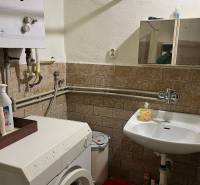 A bathroom in a family house with a washing machine, a sink, and a gas boiler.
