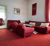 Living room in a family house with a red carpet, sofa, and armchairs.