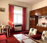 Living room of a family house with a red carpet, curtains, and furniture.