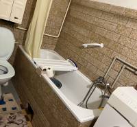 Bathroom in a family house, with a bathtub, washing machine, and tiles.