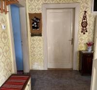 Hallway in a family house with wallpaper, wooden furniture, and wall decorations.