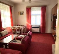 Living room in a family house with red curtains, armchairs, and a table.