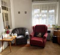 A living room corner with an antique chair and a flower table in a family house.