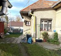 A family house on Partizánska Street in Detva with a yard, plants, and drainage pipes.
