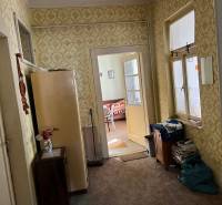Interior of a family house with older furniture, patterned wallpaper, and a view into the room.
