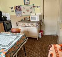 A kitchen in a family house, with a stove, microwave, and a floral tablecloth on the table.