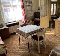 A room in a family house with a carpet, a table, and a television in the countryside.