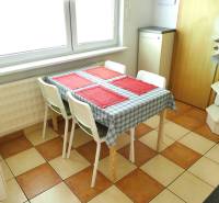 Dining room with a wooden table and four chairs in a three-room apartment, checkered floor.