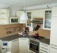 A kitchen in a 3-room apartment with a kitchen unit, appliances, and orange tiles.