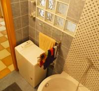A bathroom in a 3-room apartment with a washing machine, a bathtub, and a mosaic tiled wall.
