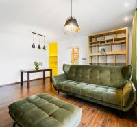Living room of a 4-room apartment with wooden flooring, a green sofa, and a shelving system.