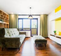 Living room in a 4-room apartment with a sofa, shelves, and a large window.