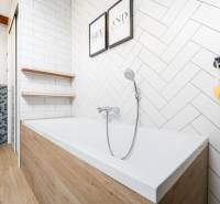 A bathroom with a shower and a bathtub in a 4-room apartment, decorative tiles on the walls.