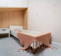 A children's room with ceiling storage and a bed with a pillow and blanket in a 4-room apartment.