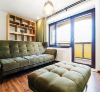 Living room with a green sofa and an open bookshelf in a four-room apartment.