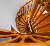 Wooden spiral staircase in a 4-room apartment with a railing.