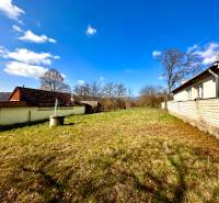Construction of houses in Moravské Lieskové, showing grassy plots and surrounding buildings.