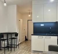 A kitchen in a studio apartment with minimalist equipment and a dining nook.