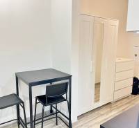 Dining area with two chairs and white storage furniture in a studio apartment.