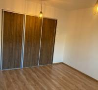 A room in a 3-room apartment with a wooden floor and a built-in wardrobe, light from the chandelier.
