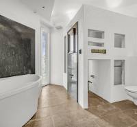 White bathroom with a bathtub, shower, and wall-hung toilet in commercial premises.