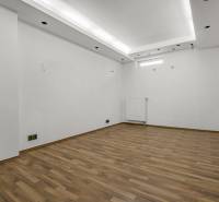 Empty commercial spaces with white walls and wooden flooring.