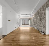 Commercial premises with wooden flooring and a stone wall, suitable for various uses.