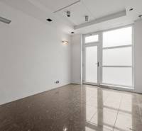 Commercial premises with light walls and large glass doors, tiles, radiator.