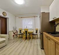 Kitchen and dining area in a 2-room apartment with light furniture and wooden flooring.