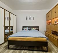 Bedroom in a 2-room apartment with a double bed, built-in wardrobe, and wooden wall unit.