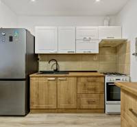 A kitchen with a stove and a refrigerator in a 2-room apartment.
