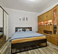 A bedroom in a 2-room apartment with a double bed, wardrobes, and a decorative shelving system.