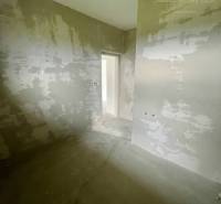 An unfinished room in a family house with unfinished plaster and a concrete floor.