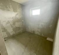 A room in a family house with bare walls, a small window, a light source without a lampshade.
