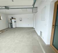 A garage in a family house with white walls and large light tiles.