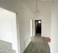 A hallway in a family house with white walls and a concrete floor.