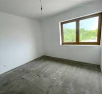A room in a family house with white walls and a large window.