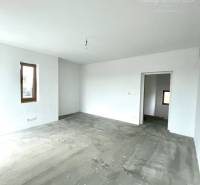 A spacious room in a family house with a concrete floor and white walls.