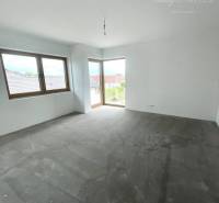 An empty room with a gray floor and two windows in a family house.
