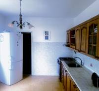 A kitchen in a 3-room apartment with rustic wooden cabinets and a white refrigerator.