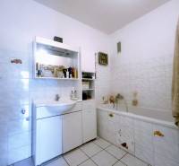 A bathroom in a 3-room apartment with a bathtub, sink, and storage space.
