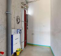 An empty bathroom on the ground floor of a family house with installations and piping.