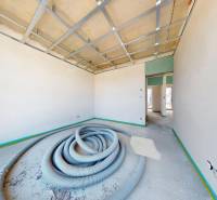 A construction site in a family house with bare walls and a ceiling with pipes on the floor.